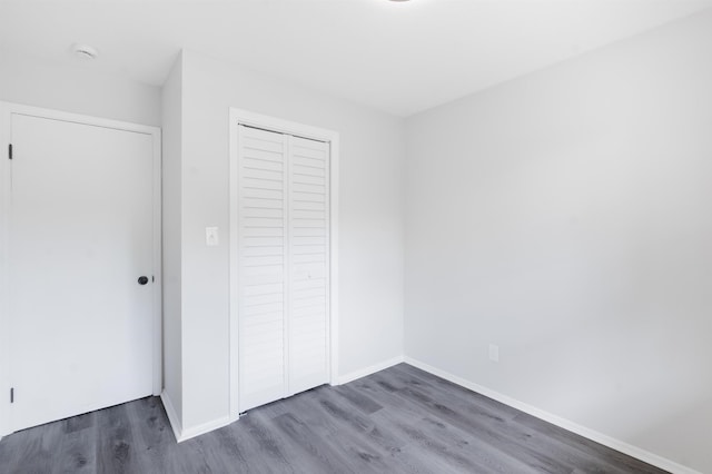 unfurnished bedroom with baseboards, wood finished floors, and a closet