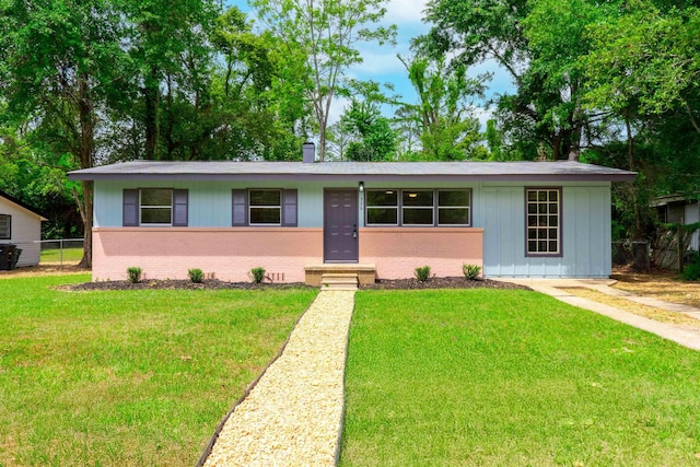 view of front of house featuring fence, brick siding, entry steps, board and batten siding, and a front yard