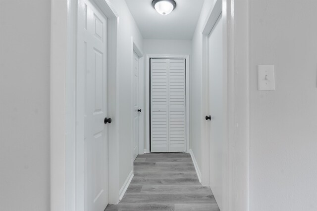 hallway with light wood finished floors and baseboards