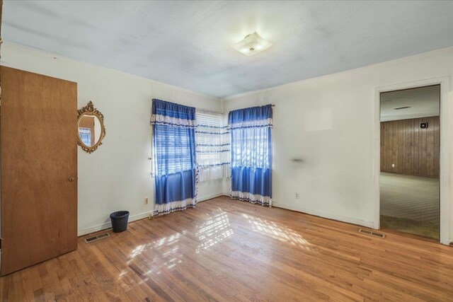 unfurnished room featuring visible vents, baseboards, and wood finished floors