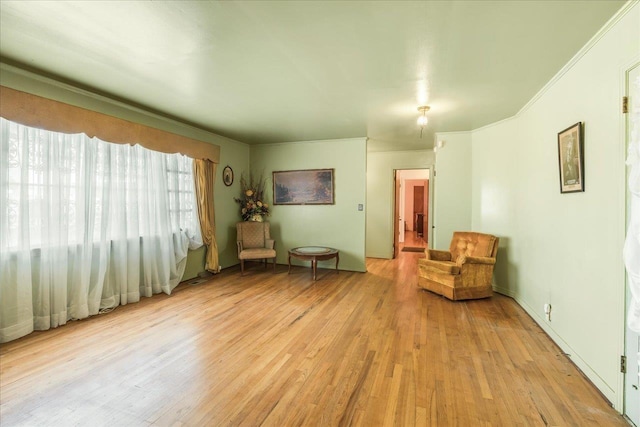 living area with crown molding and light wood-style flooring