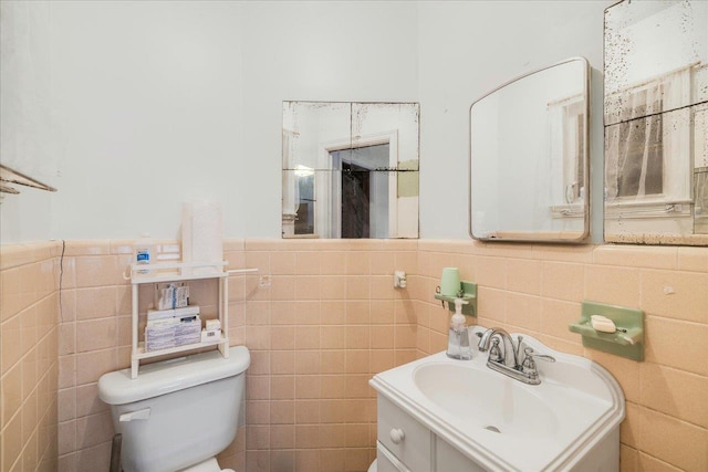 bathroom featuring vanity, tile walls, toilet, and a wainscoted wall