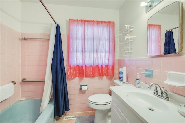 bathroom featuring visible vents, shower / bathtub combination with curtain, toilet, tile walls, and vanity