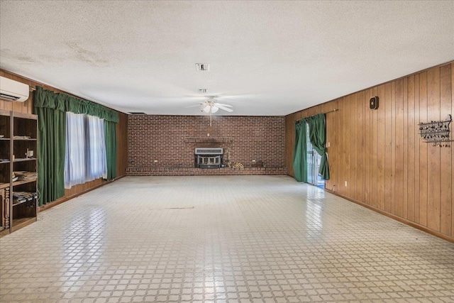 unfurnished living room featuring tile patterned floors, wooden walls, a textured ceiling, and a wall mounted air conditioner