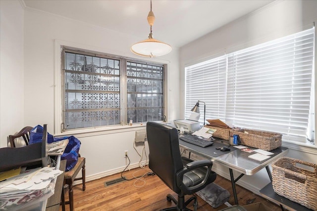 office area with visible vents, crown molding, baseboards, and wood finished floors