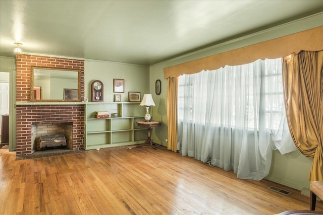 living room featuring wood finished floors, a fireplace, and visible vents