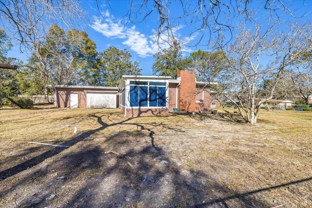 back of property with brick siding, a chimney, and a yard