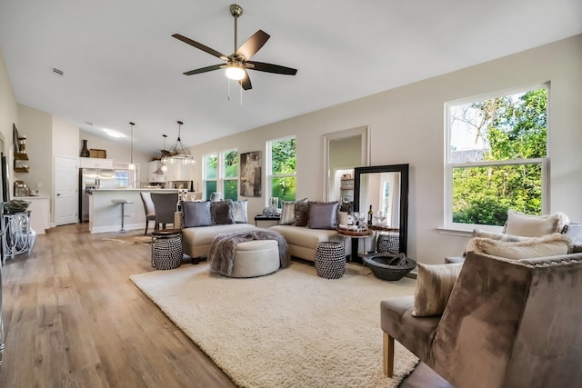 living room featuring lofted ceiling, light wood-style flooring, and a ceiling fan