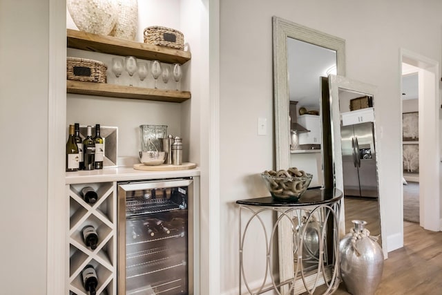 bar with stainless steel fridge, wine cooler, and wood finished floors