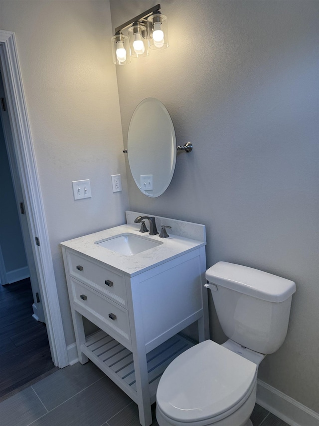 half bathroom featuring vanity, toilet, and baseboards