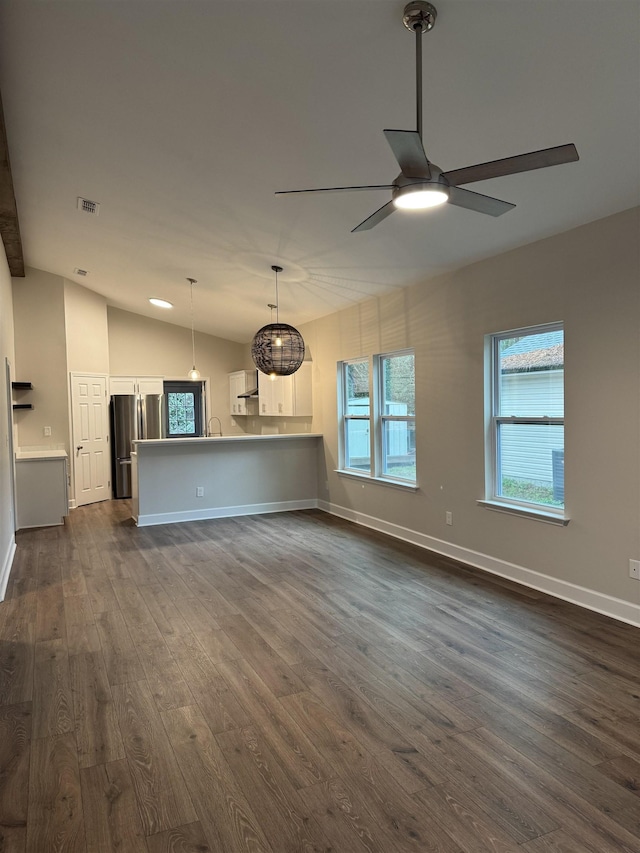 unfurnished living room with a ceiling fan, a wealth of natural light, dark wood-style flooring, and vaulted ceiling