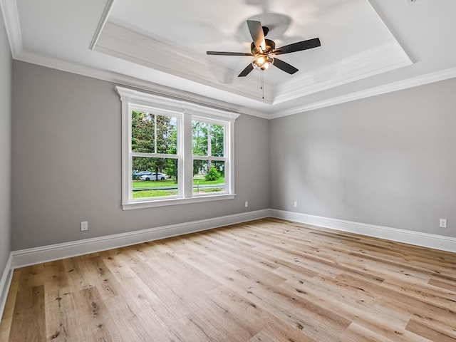 unfurnished room with a tray ceiling, crown molding, ceiling fan, and light wood-type flooring