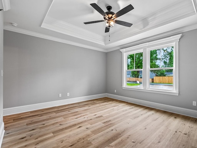 unfurnished room with ceiling fan, a raised ceiling, ornamental molding, and light hardwood / wood-style flooring