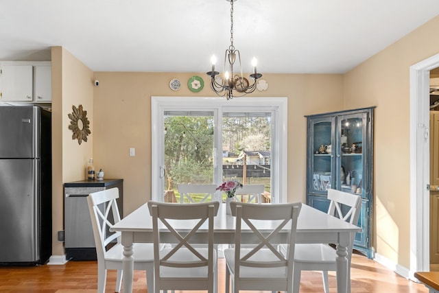 dining area featuring baseboards, light wood finished floors, and a notable chandelier