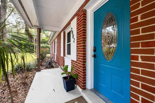 entrance to property with covered porch and brick siding