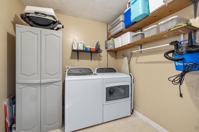 clothes washing area featuring laundry area, washing machine and dryer, baseboards, and light floors