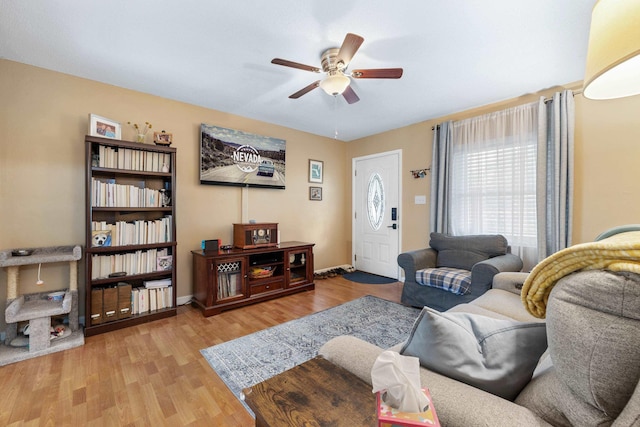 living area featuring wood finished floors, a ceiling fan, and baseboards