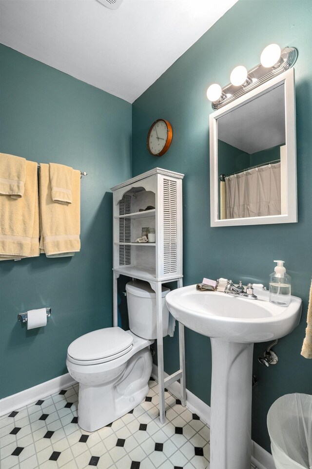 bathroom with baseboards and toilet