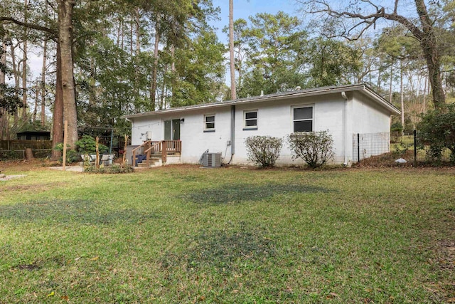 rear view of property featuring fence, central AC unit, and a yard