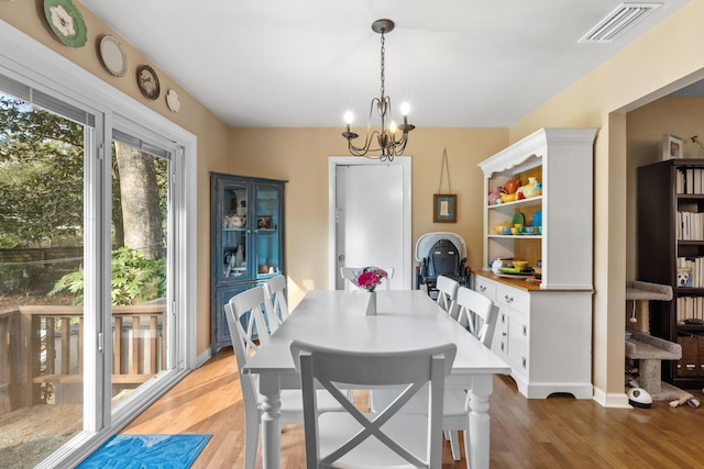 dining area featuring light wood-style floors, baseboards, visible vents, and a chandelier