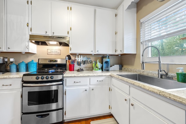 kitchen featuring white cabinets, stainless steel electric range, light countertops, under cabinet range hood, and a sink