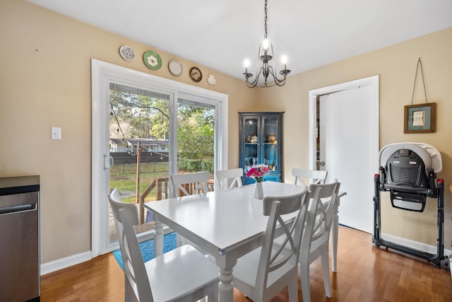 dining room featuring a notable chandelier, baseboards, and wood finished floors