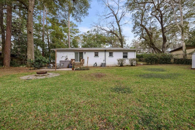 back of property with an outdoor fire pit, a patio area, fence, and a lawn