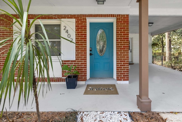 entrance to property with covered porch and brick siding