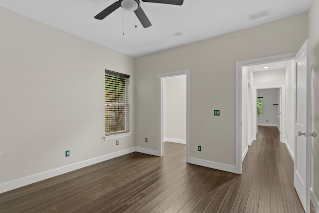 empty room with plenty of natural light, dark hardwood / wood-style floors, and ceiling fan