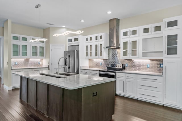 kitchen with wall chimney exhaust hood, white cabinetry, a center island with sink, appliances with stainless steel finishes, and light stone countertops