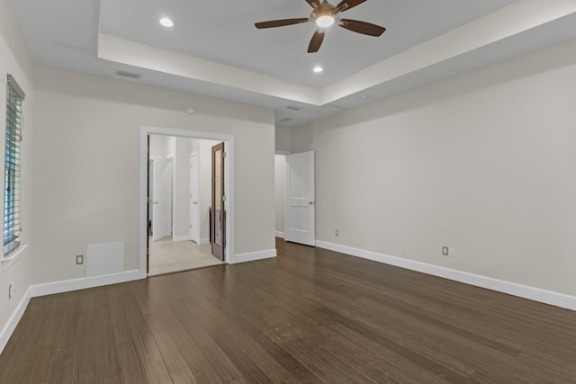 unfurnished bedroom featuring wood-type flooring, a raised ceiling, and ceiling fan