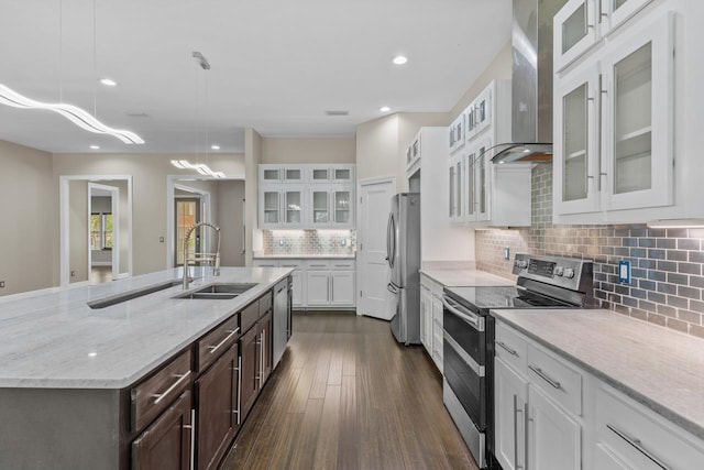 kitchen with sink, wall chimney range hood, white cabinetry, hanging light fixtures, and stainless steel appliances