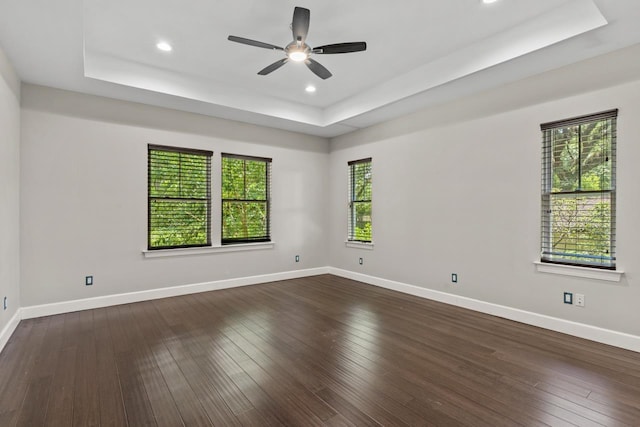 spare room featuring a raised ceiling, dark hardwood / wood-style floors, and ceiling fan