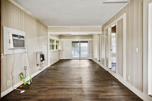 interior space featuring a wall unit AC, heating unit, a textured ceiling, and dark hardwood / wood-style flooring