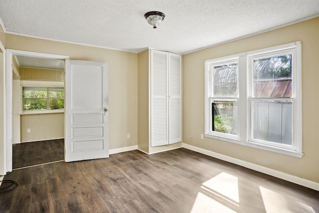 unfurnished bedroom featuring multiple windows, dark wood-type flooring, and a closet