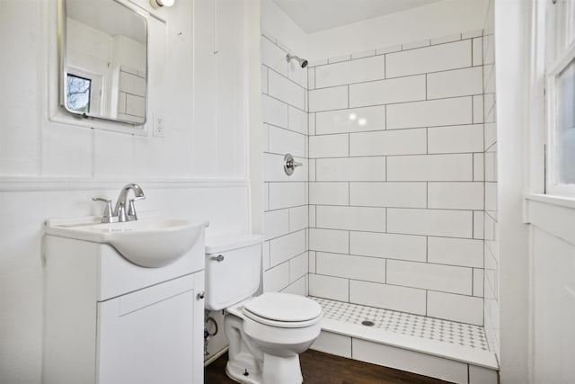 bathroom with tiled shower, vanity, toilet, and hardwood / wood-style floors