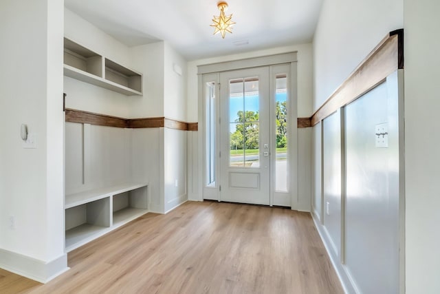 mudroom with built in shelves and light hardwood / wood-style flooring