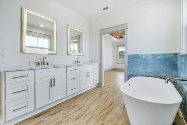 bathroom featuring a tub, hardwood / wood-style floors, vanity, and tile walls