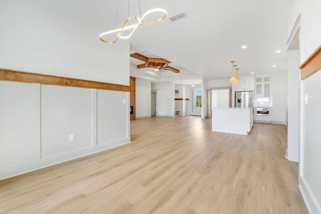 unfurnished living room featuring ceiling fan with notable chandelier and light hardwood / wood-style floors