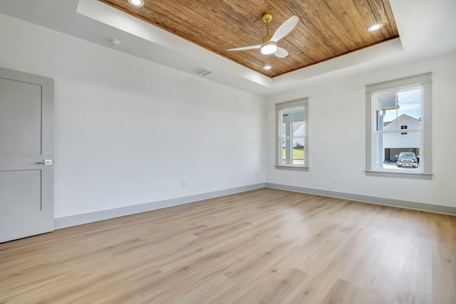 unfurnished room featuring a tray ceiling, ceiling fan, wooden ceiling, and light wood-type flooring