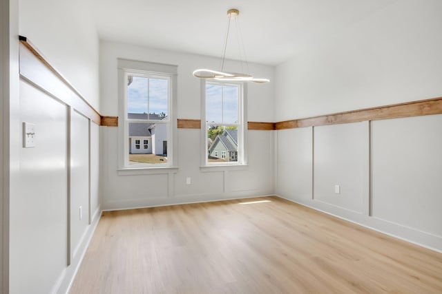 unfurnished room with light wood-type flooring and a notable chandelier