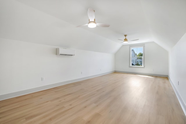 additional living space featuring lofted ceiling, ceiling fan, light wood-type flooring, and an AC wall unit