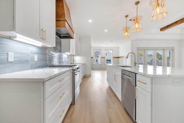 kitchen featuring appliances with stainless steel finishes, a spacious island, sink, decorative light fixtures, and white cabinets