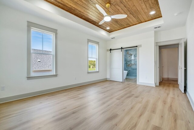 unfurnished bedroom with ensuite bath, ceiling fan, a barn door, a tray ceiling, and wood ceiling