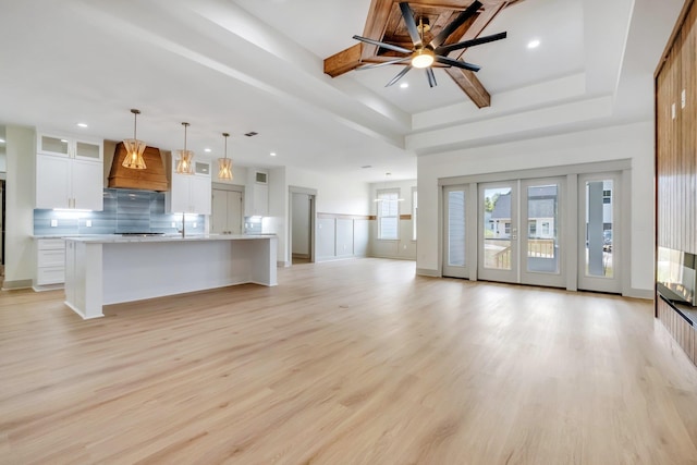 unfurnished living room featuring ceiling fan, light hardwood / wood-style floors, and a raised ceiling