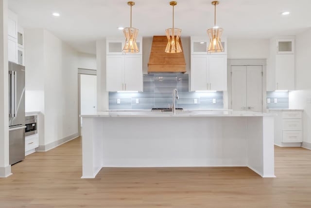 kitchen with decorative light fixtures, light wood-type flooring, white cabinetry, and sink