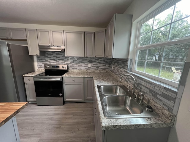 kitchen with stainless steel appliances, gray cabinets, a sink, and under cabinet range hood