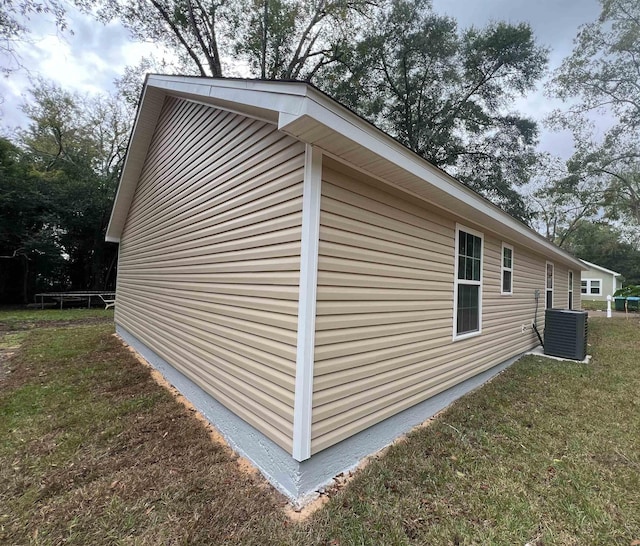 view of side of property featuring central AC unit and a lawn