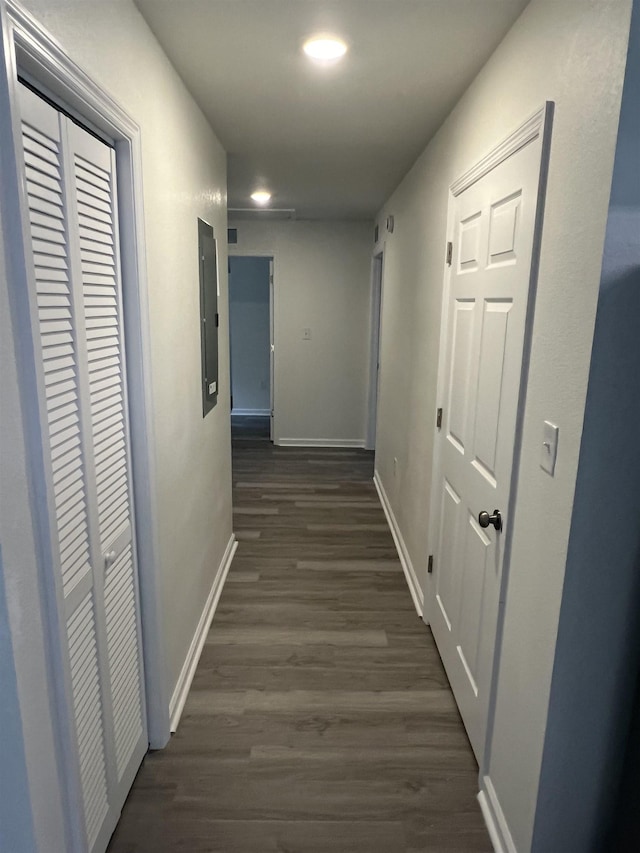 hallway featuring dark wood-style floors, electric panel, and baseboards