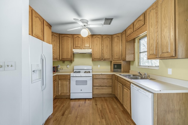 kitchen featuring visible vents, light wood-style floors, a sink, white appliances, and under cabinet range hood